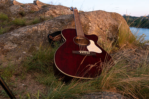Music: acoustic guitar on the rock. guitar at the sunset, music backgro Guitar resting on a rock
