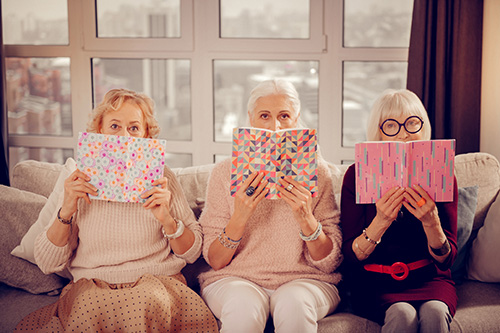 Three senior women reading a book