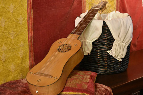 Guitar leaning a piece of furniture draped in a white shirt