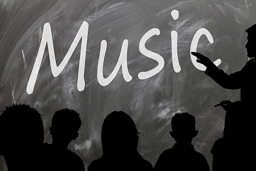 "Music" written on a board with audience in silhouette.