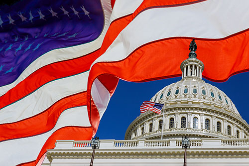American flag waves alongside US Capitol dome