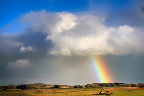 Rainbow arcs from cloud over the horizon.