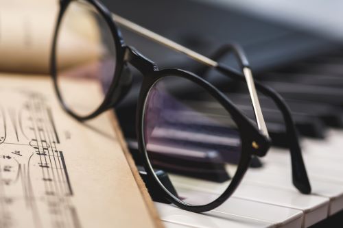 Sheet music with glasses resting on pain keys
