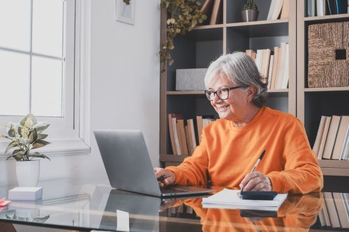 Woman in orange sweater working on a laptop
