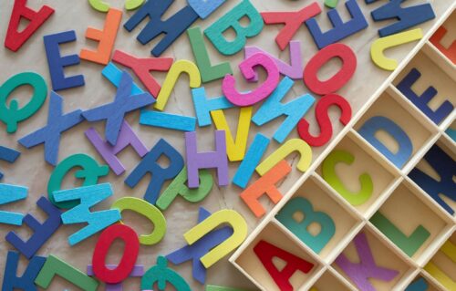 Colored alphabet letters lay outside box for sorting them.