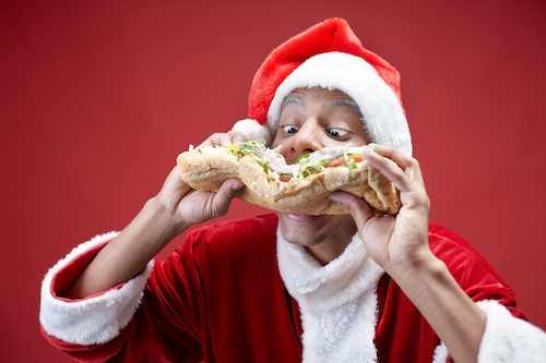Hungry Santa man biting big sandwich