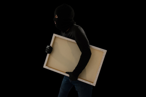 Dangerous criminal with a black mask stealing a valuable painting against a dark background