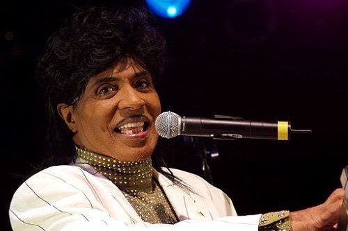 Photo of musical artist Little Richard sitting at a microphone