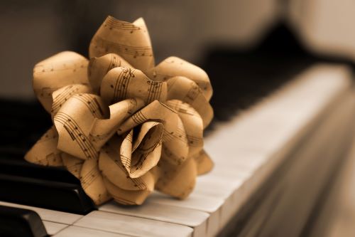 Sheet music folded into shape of a flower, atop a pianio