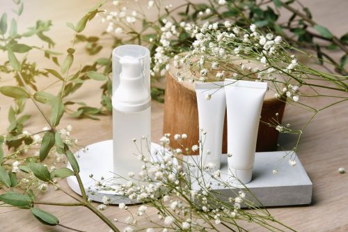 3 white containers of skin products surrounded by herbs