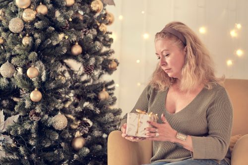 Pensive woman sitting in front of Christmas tree