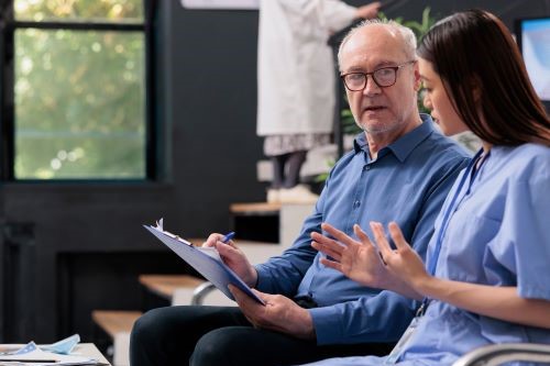 Health care professional talking with man holding a clipboard