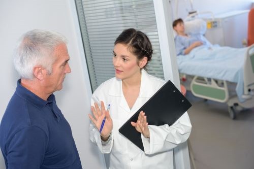 Doctor talking to patient's family member outside hospital room