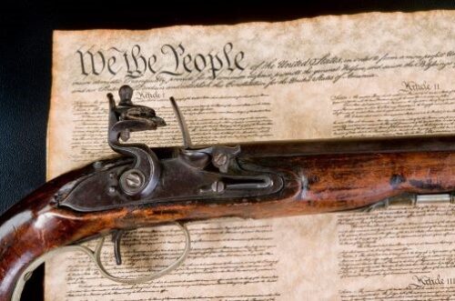 Copy of the Constitution with an old-fashioned gun laid across it