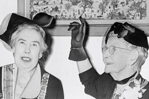 Photo of Grandma Moses pointing to one of her paintings