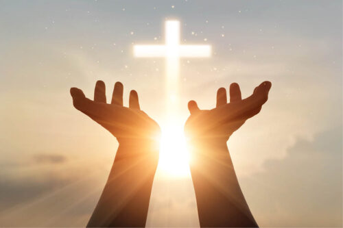 Hands stretched toward sky, image of a cross