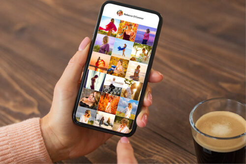 Person holding iPhone, screen shows their photo library