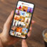 Person holding iPhone, screen shows their photo library