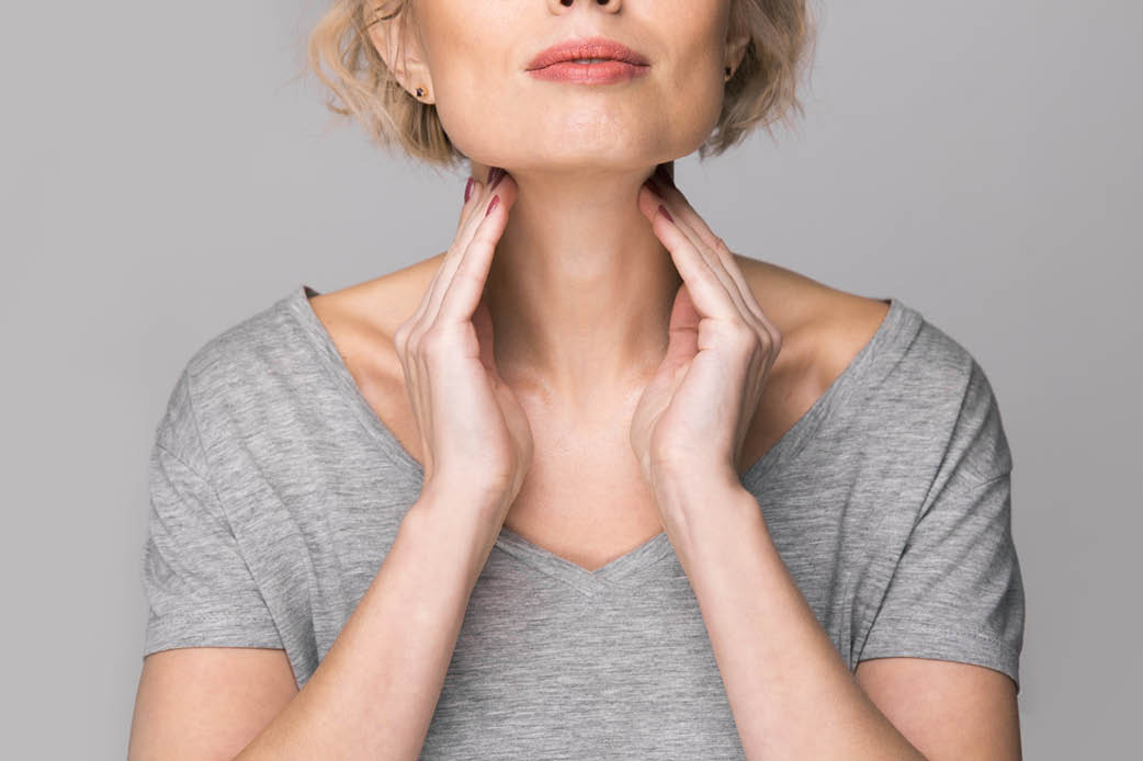 Thyroid health Woman with her hands on her thyroid