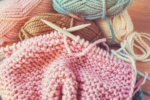 Up close photo of knitting needles and a pink knitted product