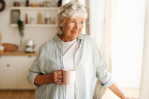 Woman holding coffee cup looking out window