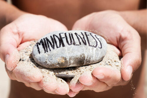 hands holding a stone with "Mindfulness" written on it
