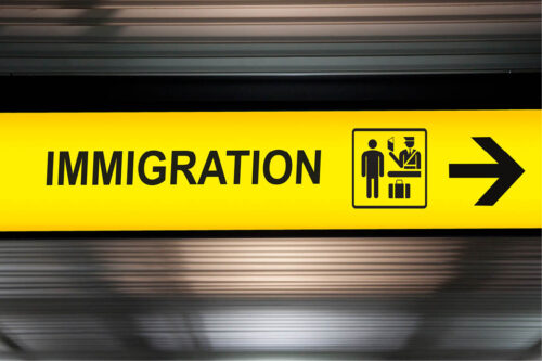 Glowing sign that has an arrow pointing right and the word "Immigration"