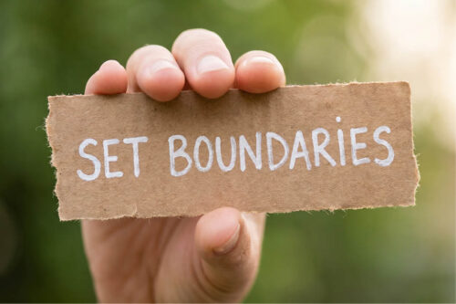 hand holding up cardboard sign that says "Set Boundaries"
