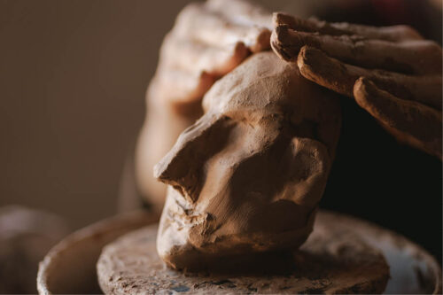hands molding a clay sculpture of a face