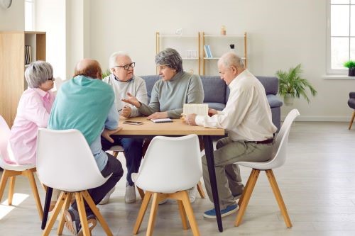 Older adults sitting at a table discussing a book