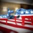 Donkey and elephant facing each other, each are painting in American flag colors